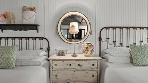 A bedroom with two beds, a dresser, a mirror, and decorative items. - Carriage Haus, Downtown, Pet Friendly! (New Braunfels)