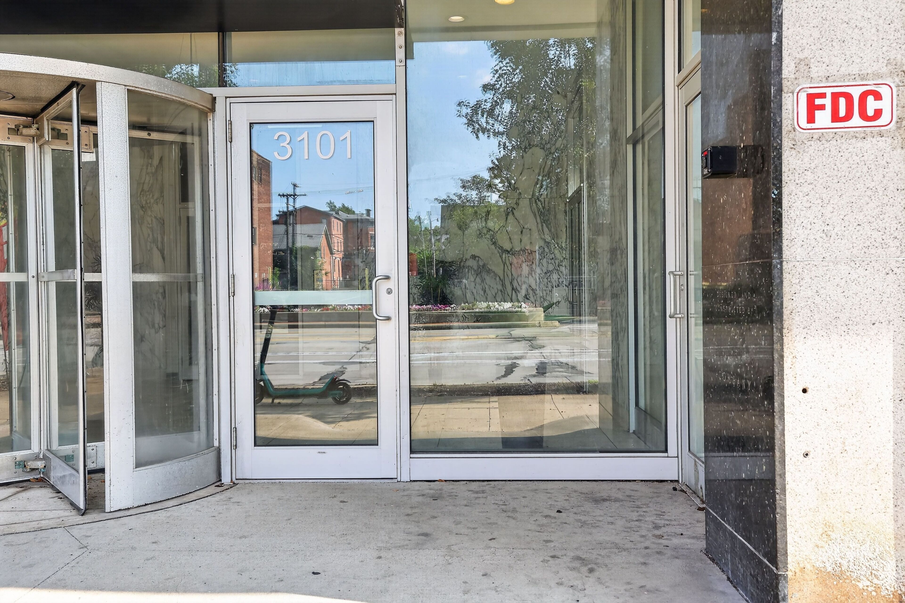 Une entrée d’immeuble avec une porte vitrée portant l’inscription « 3101 » et un panneau « FDC ».