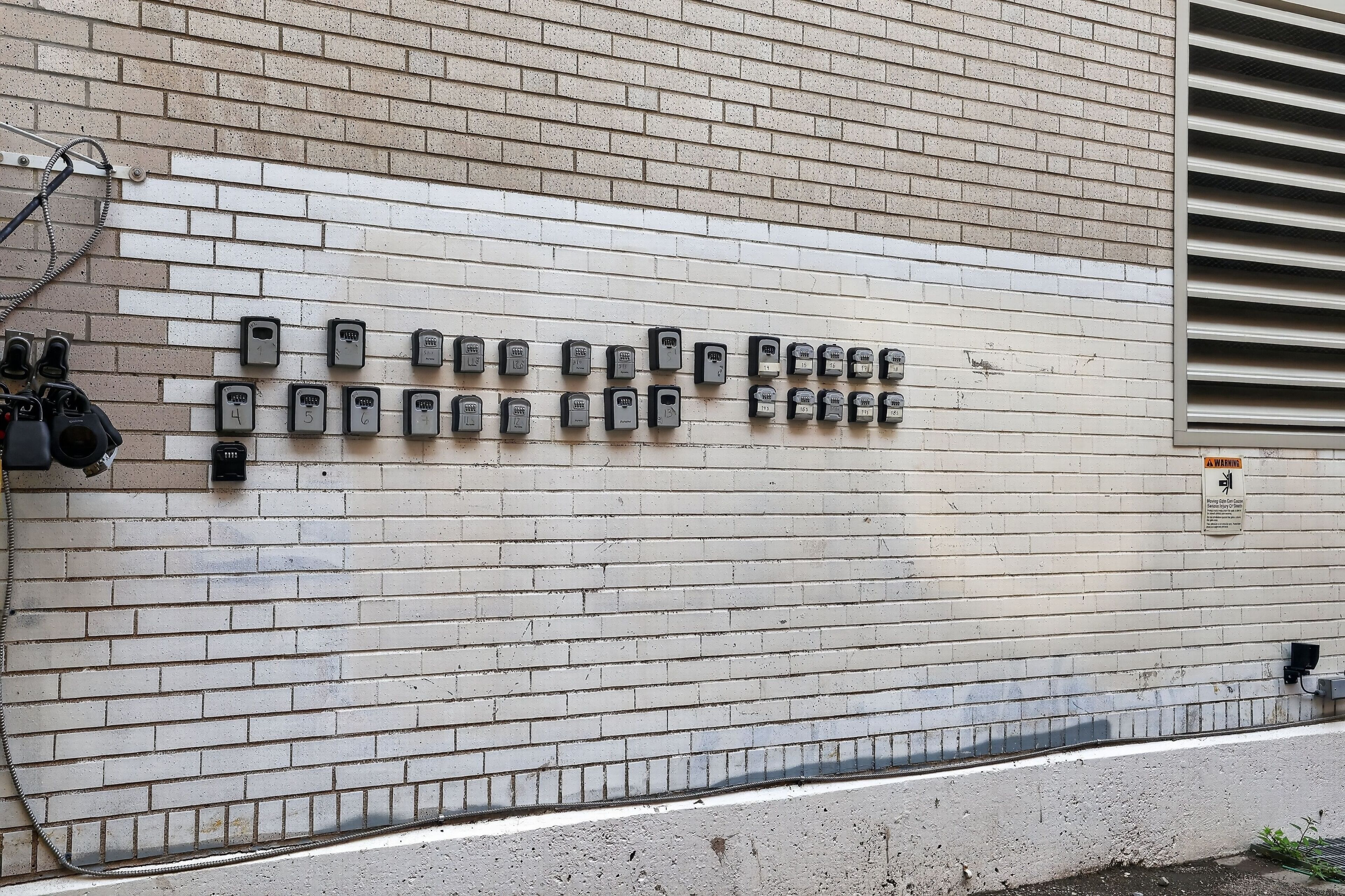 Un mur muni de plusieurs interphones et d’un panneau d’avertissement.
