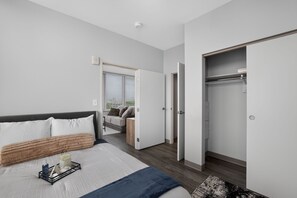 Ein modernes Schlafzimmer mit einem großen Bett, einem Nachttisch, einem Kleiderschrank und einer Tür zu einem Badezimmer.