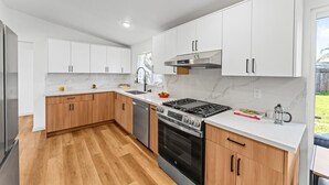 A modern kitchen with white cabinets, a stainless steel stove, and a wooden countertop.