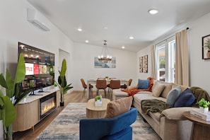 A modern living room with a flat-screen TV, a dining area with a wooden table and chairs, and a large window with curtains. - 4BD 3BA Modern Home with Backyard. Near SF, Concord, Oakland & Napa Winery (Concord)