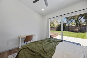 A bedroom with a bed, a desk, and a chair. There is a sliding glass door leading to a backyard. - 4BD 3BA Modern Home with Backyard. Near SF, Concord, Oakland & Napa Winery (Concord)