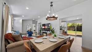 A modern dining area with a wooden table, chairs, and a chandelier.