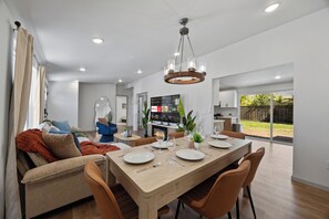 A modern dining area with a wooden table, chairs, and a chandelier.