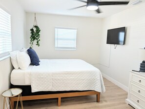 A bedroom with a bed, a hanging plant, a television, and a dresser. - A Haven of Sun and Fun in Largo; A Private Oasis in the heart of everything (Largo)
