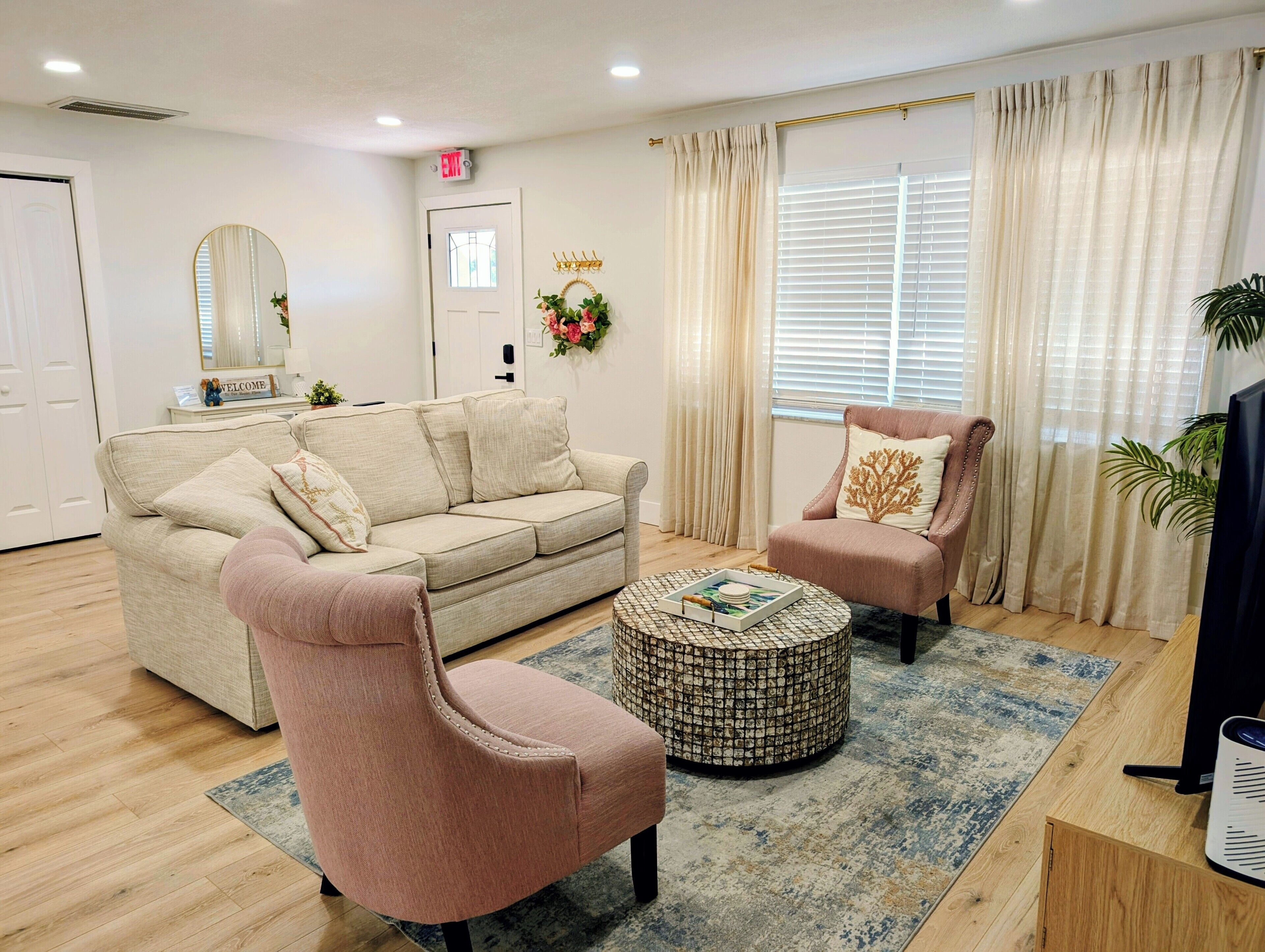 Ein Wohnzimmer mit einer Couch, einem Sessel, einem Couchtisch und einem Fernseher.