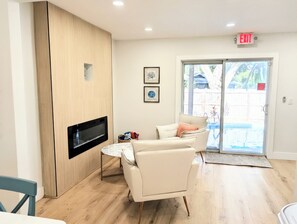 A modern living room with a flat-screen TV, a sofa, a coffee table, and a sliding glass door leading to an outdoor area. - A Haven of Sun and Fun in Largo; A Private Oasis in the heart of everything (Largo)