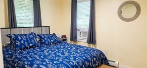 A bedroom with a bed, a nightstand, a wall clock, and a window with blinds. - Comfort and Convenience in Renovated 3 Bedroom Home near UConn (Tolland)