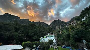 Un paisaje montañoso con una casa rodeada de vegetación.