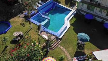 Un área de piscina con varias piscinas, sillas de descanso y sombrillas.