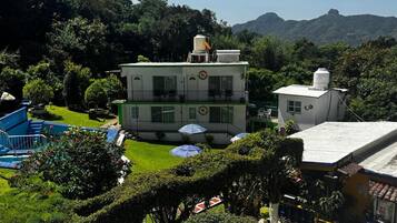 Un edificio de dos pisos con piscina y sombrillas en el patio.