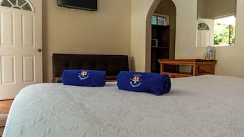 Habitación de hotel con cama, dos toallas con diseño de seta, televisor en la pared y vista a zonas verdes.