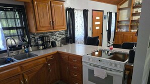A kitchen with wooden cabinets, a white countertop, a stove, and a sink. - Peaceful 1-bedroom house with AC in charming Pittsburg within walking of PSU (Pittsburg)