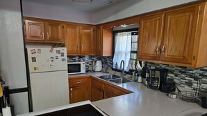 Une cuisine avec des meubles de rangement en bois, un réfrigérateur, un four à micro-ondes, un évier et une cuisinière.