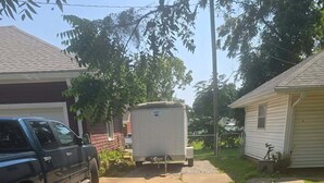 A residential driveway with a parked SUV, a white trailer, and a house with a garage. - Peaceful 1-bedroom house with AC in charming Pittsburg within walking of PSU (Pittsburg)