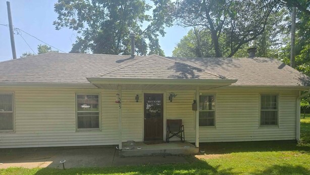 A single-story house with a front porch, a mailbox, and a small front yard.