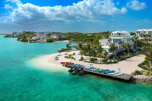 A coastal resort with a sandy beach, a dock with boats, and buildings with a modern design. - Rooftop Villa w/ Pool & Hot Tub in Chalk Sound (Providenciales)