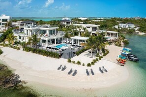A beachfront property with multiple modern villas, a swimming pool, and a beach with lounge chairs. - Rooftop Villa w/ Pool & Hot Tub in Chalk Sound (Providenciales)
