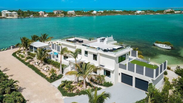 Ein modernes Strandhaus mit flachem Dach, einem Schwimmbad und Meerblick.