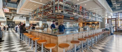 Un espace bar avec des tabourets et des étagères remplies de bouteilles.