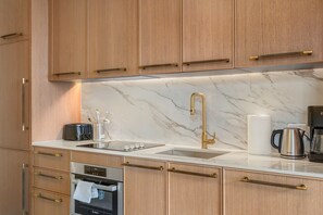 A modern kitchen with wooden cabinets, a stainless steel sink, a Bosch oven, and a marble countertop. - Luxury Miami 1BR Apt with Pool  (Miami)