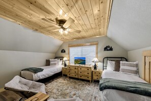 Ein Schlafzimmer mit zwei Betten, einem Deckenventilator, einem Fenster mit Blick und einem Schminktisch.