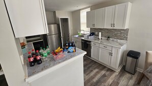 Cocina moderna con armarios blancos, refrigerador de acero inoxidable y encimera de mármol.
