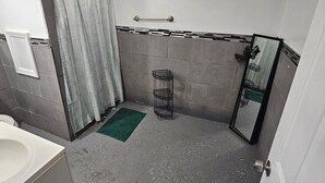 Baño con inodoro, lavabo, ducha y toallero.