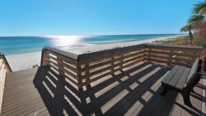 Eine Holzterrasse mit Geländer, die auf einen Strand blickt.