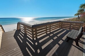 Eine Holzterrasse mit Geländer, die auf einen Strand blickt.