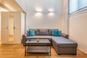 Ein modernes Wohnzimmer mit einem grauen Ecksofa, einem Glastisch und Türkis-Kissen.