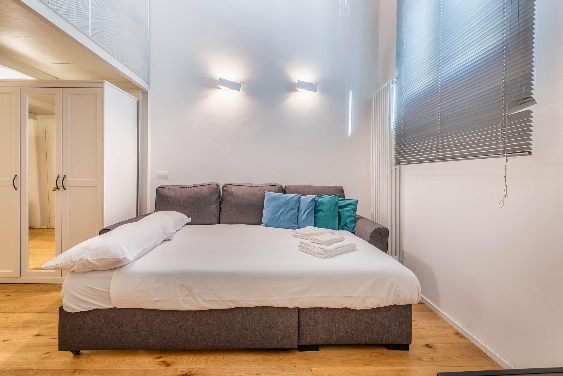 Une chambre à coucher avec un lit, des oreillers et une fenêtre équipée de stores.