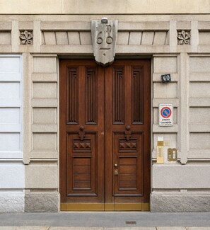 A double wooden door with a stone facade, a no parking sign, and a street number '60'. - Cozy Apartment Milano | Bocconi & City Center (Milan)
