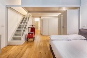 A bedroom with a bed, a red suitcase, a staircase, and a wardrobe. - Cozy Apartment Milano | Bocconi & City Center (Milan)