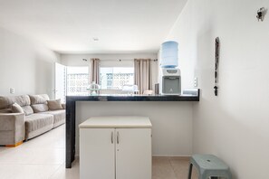A compact living space with a kitchenette, a sofa, a small fridge, and a water dispenser. - Casa Maragogi- 2Qrts e Piscina-SH162 (Maragogi)