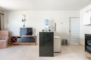 Uma sala de estar moderna com televisão de tela plana, um dispenser de água, sofá e um armário.