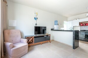 Ein modernes Wohnzimmer mit Flachbildfernseher, einem rosafarbenen Sofa und einer Holzunterhaltungseinheit.