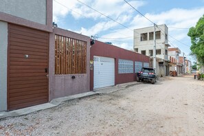 Rua residencial com casas, uma caminhonete estacionada e uma estrada de terra.