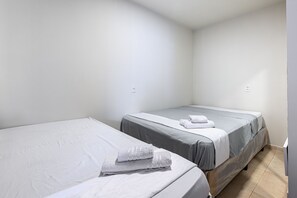 A small, clean room with two single beds, each with a grey mattress and white bedding. There are two wall sockets visible. - Casa Maragogi- 2Qrts e Piscina-SH162 (Maragogi)