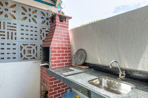 Uma cozinha com forno de tijolos, pia e painel decorativo na parede.