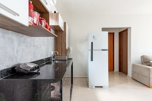 A modern kitchen with a black countertop, a built-in oven, and a white refrigerator. - Casa Maragogi- 2Qrts e Piscina-SH162 (Maragogi)
