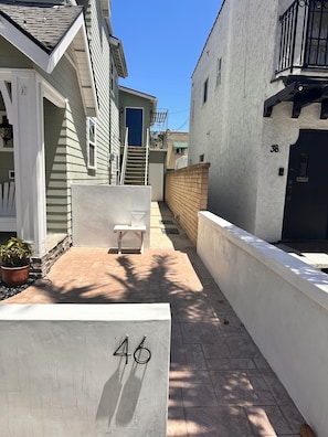 A narrow alleyway with a white building marked with the number 46, a bench, and a potted plant. - 2BDR Belmont Shore Retreat <> Steps from the Beach (Long Beach)