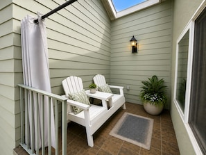 A small patio area with two Adirondack chairs, a white table, a potted plant, and a wall-mounted light fixture. - 2BDR Belmont Shore Retreat <> Steps from the Beach (Long Beach)