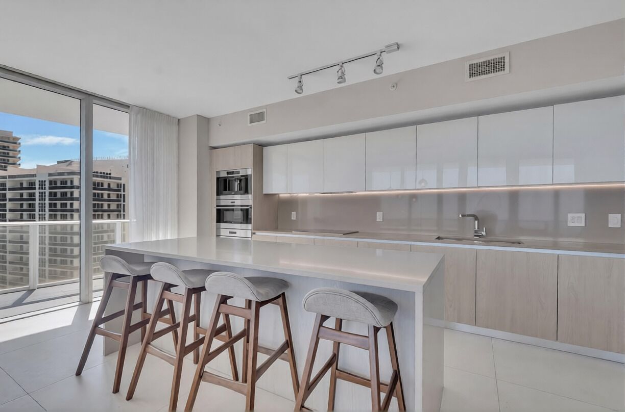 Een moderne keuken met een groot eiland, barkrukken en stadszicht.