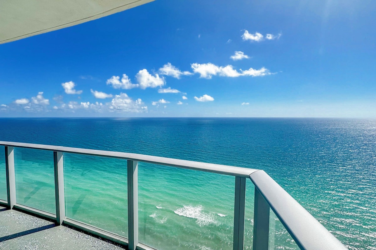 A clear view of the ocean from a balcony with a metal railing.