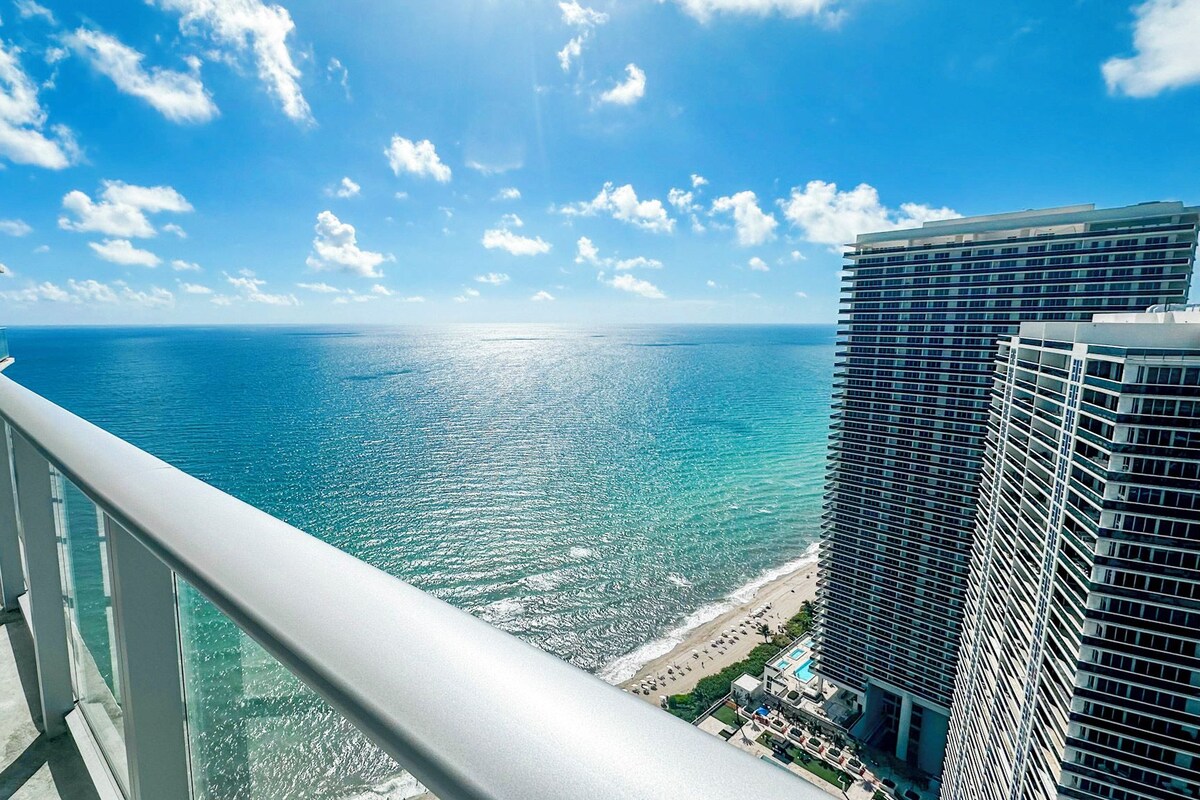 A balcony with a view of the ocean and a high-rise building.