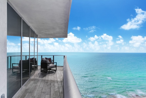 Een balkon met uitzicht op de oceaan, voorzien van stoelen en een bank.