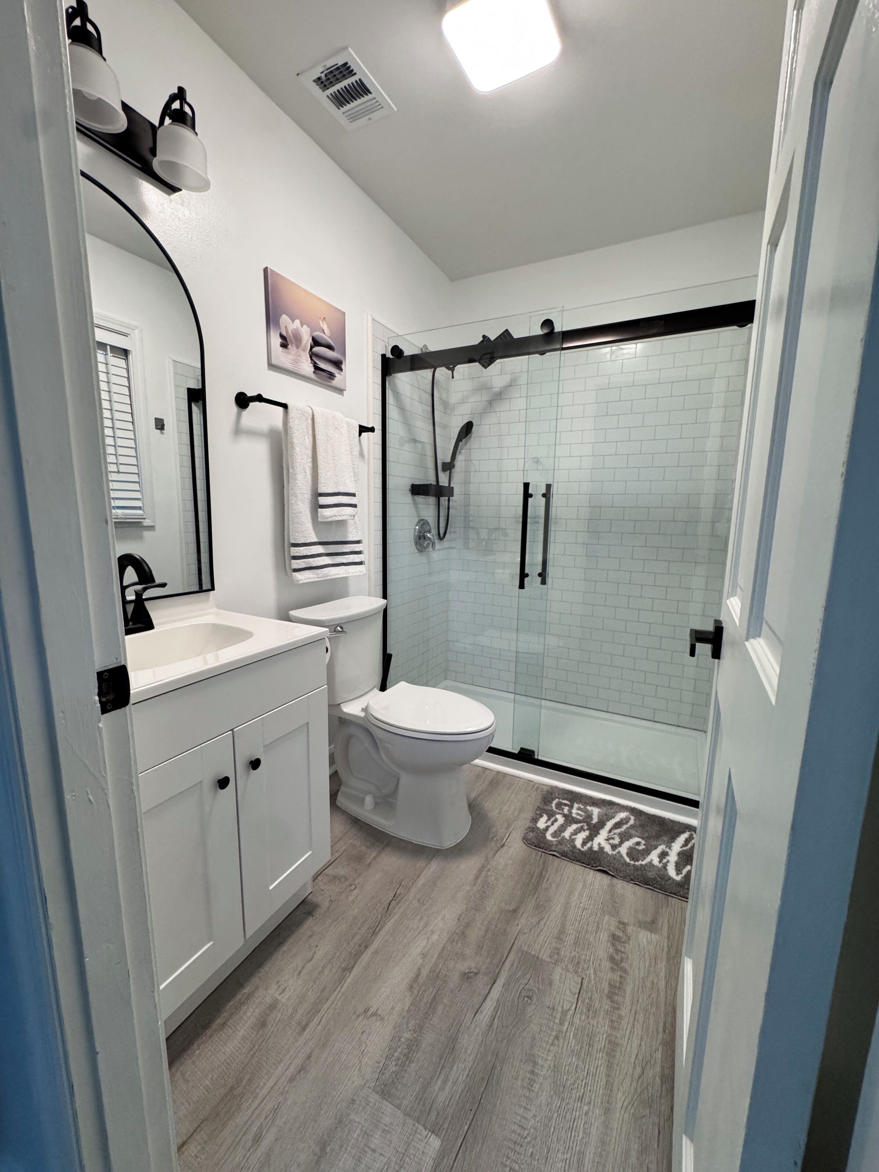 Un baño moderno con cabina de ducha de vidrio, inodoro blanco y tocador con espejo.