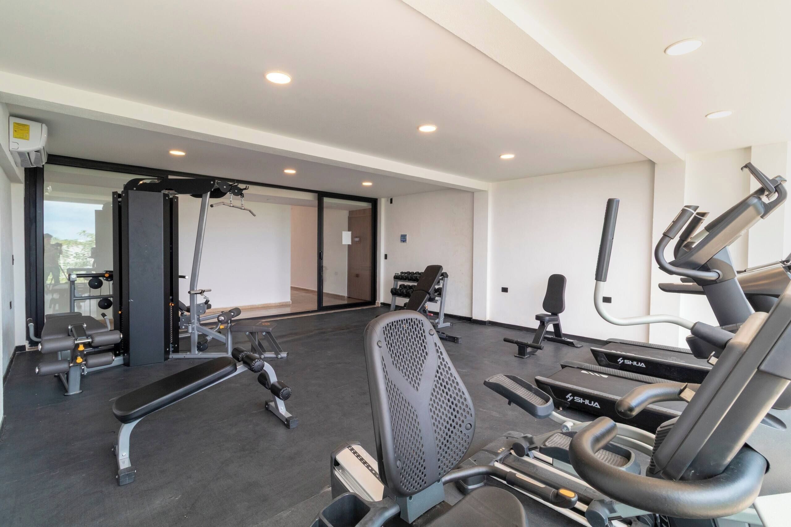 Un gimnasio con equipo de ejercicio, incluyendo cintas de correr y máquinas de pesas.